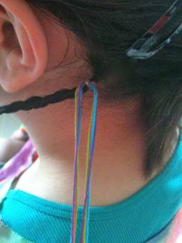 Hair wrap with friendship bracelet string, next to hair feathers.